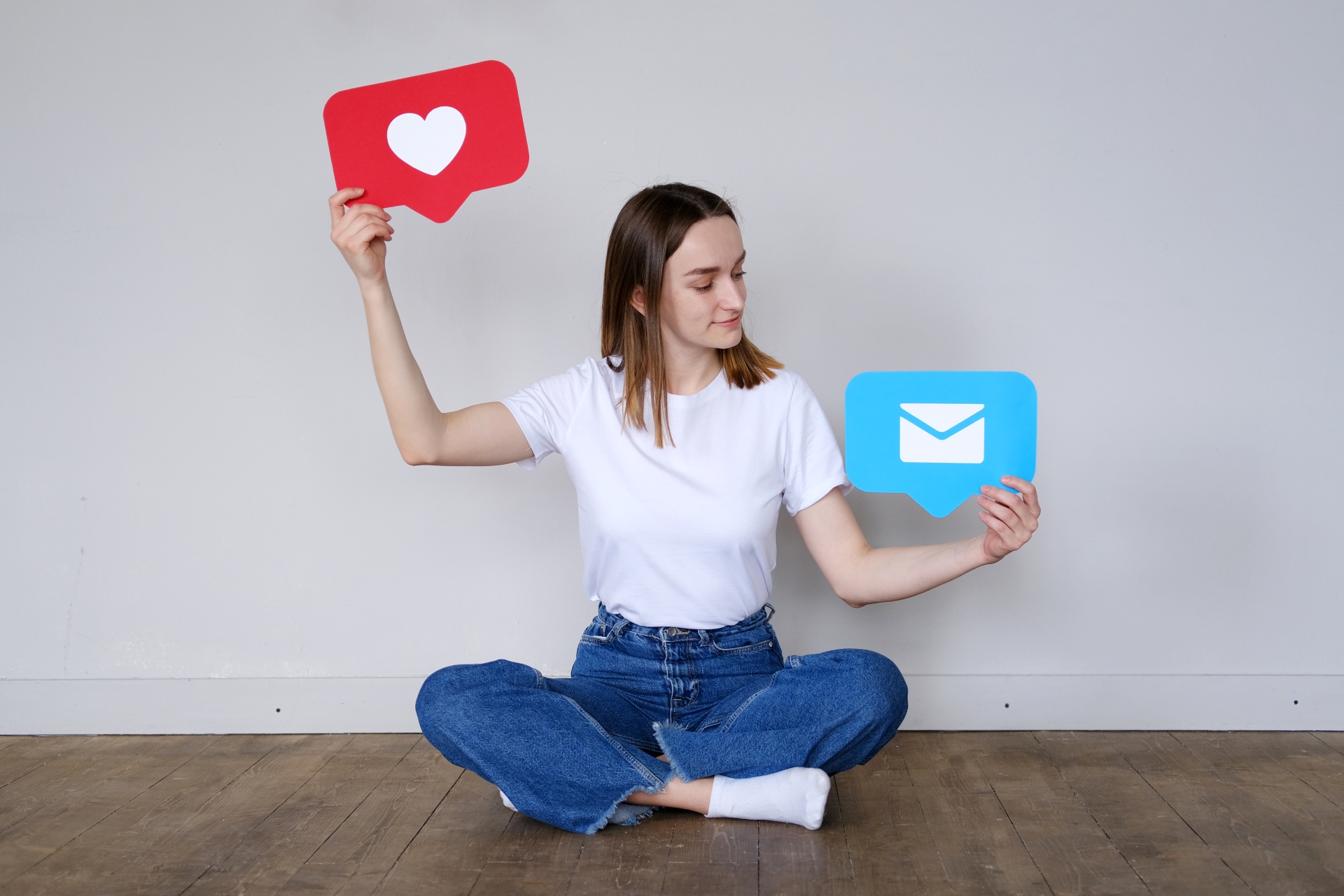 Young woman holding up a love heart icon and a message bubble icon.